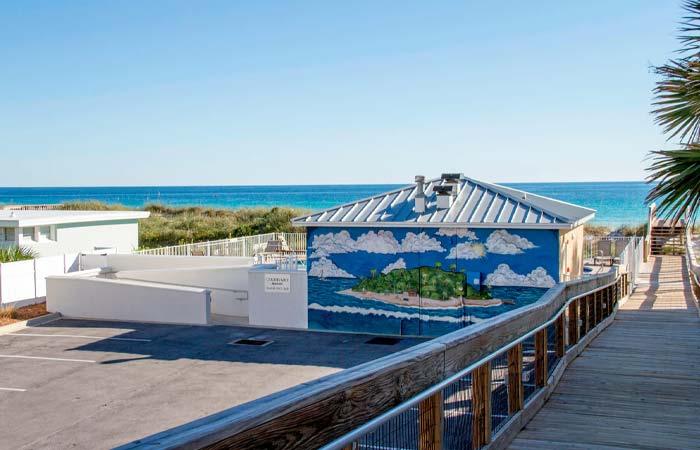Beachside Sundrift Inn with a beach mural, near the ocean by a wooden walkway and parking lot.