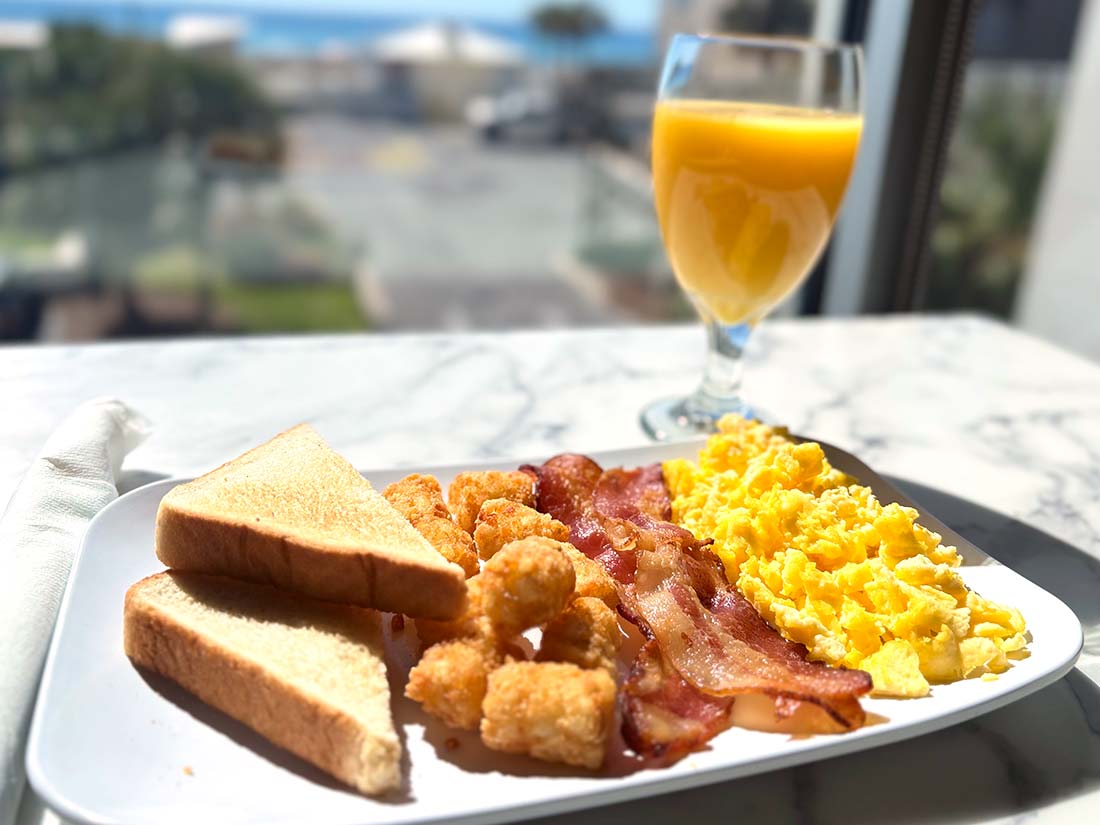 Breakfast at Sundrift Inn: toast, tater tots, bacon & eggs with OJ by your Panama City Beach Hotel window.