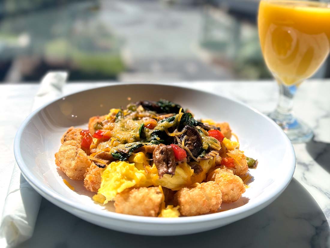 Beachside plate of scrambled eggs, tater tots, veggies, and OJ at Sundrift Inn.