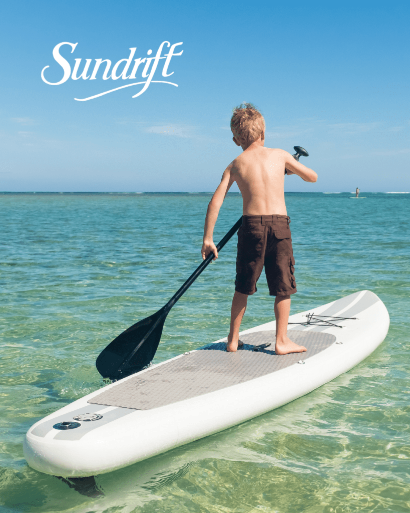 Boy paddleboarding in clear emerald water near Okaloosa Island in Fort Walton Beach Florida on the Emerald Coast