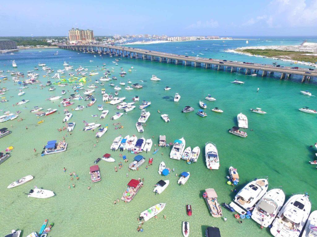 Crab Island Destin Florida aerial view with boats gathered in shallow emerald water near Destin Bridge