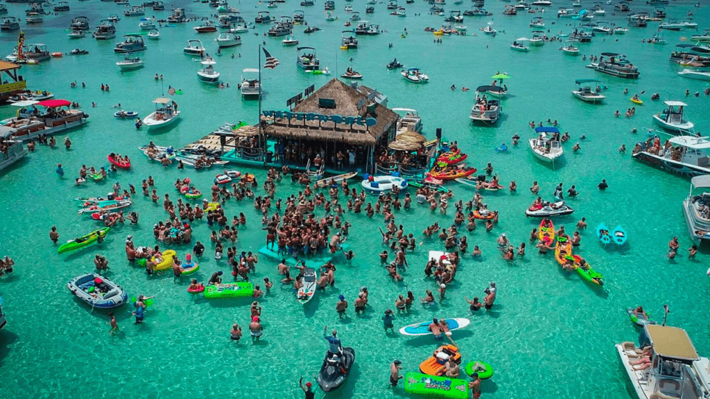 Crowds enjoying Crab Island in Destin Florida with boats floating in clear emerald water