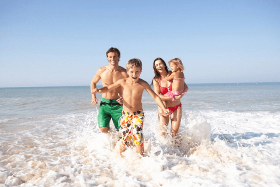 Family running through the shallow waves on Okaloosa Island beach near Fort Walton Beach Florida on the Emerald Coast