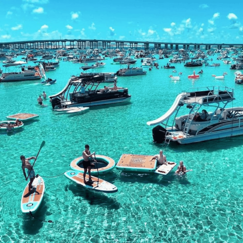 Boats gathered near Crab Island with emerald water and Destin Bridge views