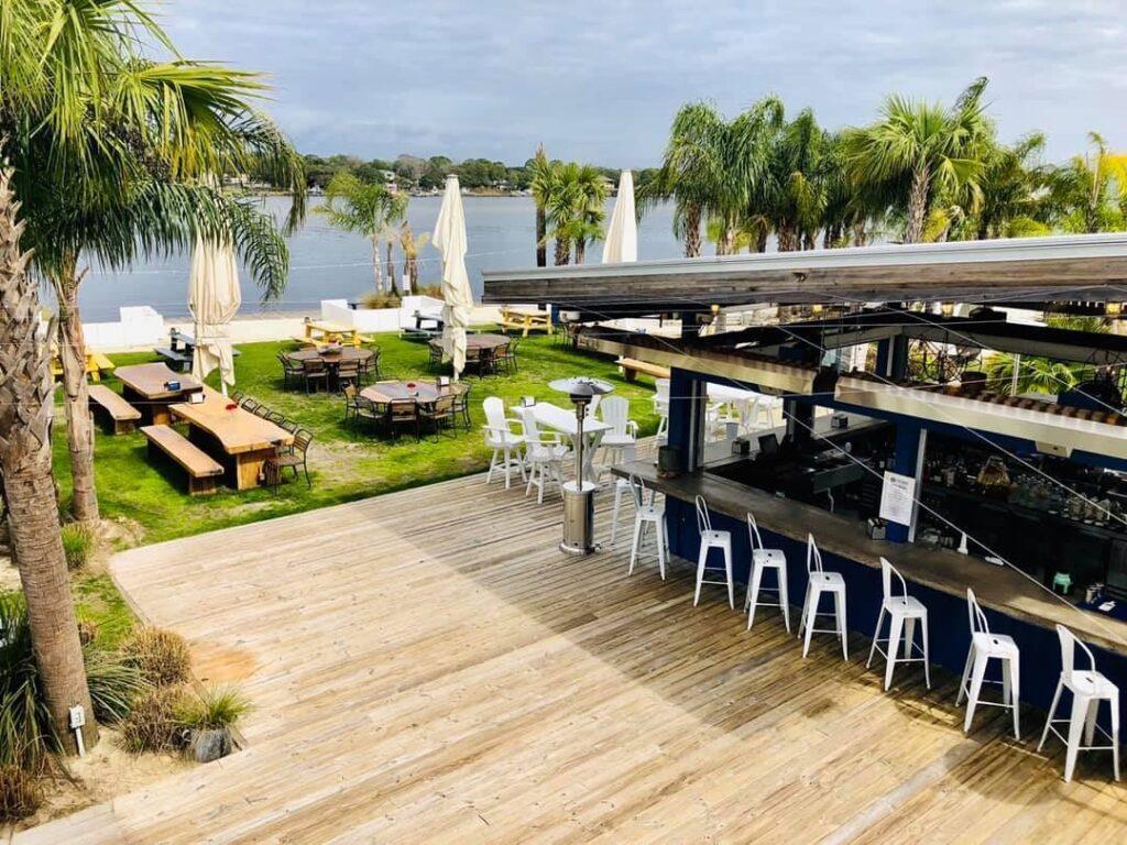 Outdoor waterfront dining at The Gulf on Okaloosa Island with palm trees and water views