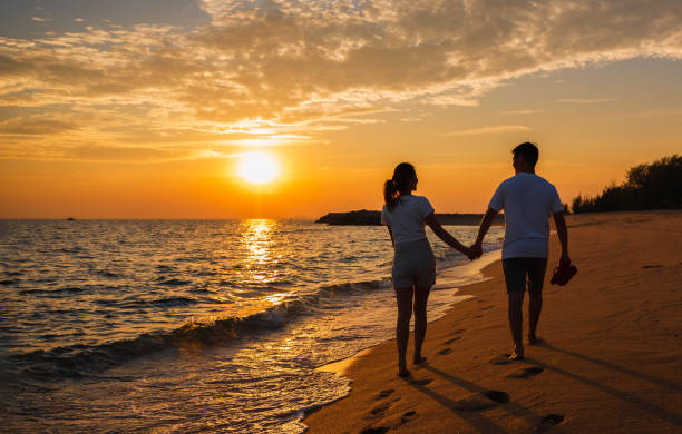 Couple enjoying sunset walk along Okaloosa Island beach near waterfront hotel
