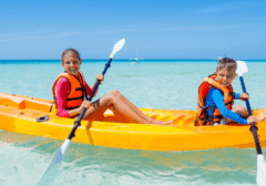 Kids kayaking in clear emerald water near Okaloosa Island at Sundrift Inn in Fort Walton Beach Florida on the Emerald Coast