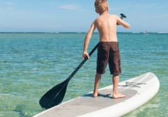 Boy paddleboarding in clear emerald water near Okaloosa Island in Fort Walton Beach Florida on the Emerald Coast