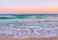 Sunset waves along Okaloosa Island beach with pink sky over the Gulf of America