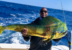 Angler holding a large mahi mahi caught during a deep sea fishing charter in Destin Florida on the Emerald Coast