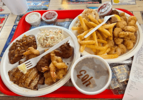 Fresh Gulf seafood platter from Stewby’s Seafood Shanty with fried fish, shrimp, hush puppies, fries, and coleslaw near Okaloosa Island in Fort Walton Beach Florida