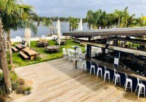 Outdoor waterfront dining at The Gulf on Okaloosa Island with palm trees and water views